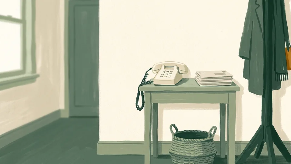 A landline phone on a hallway table beside a stack of post