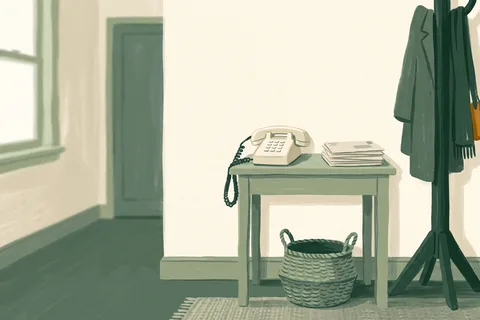 A landline phone on a hallway table beside a stack of post